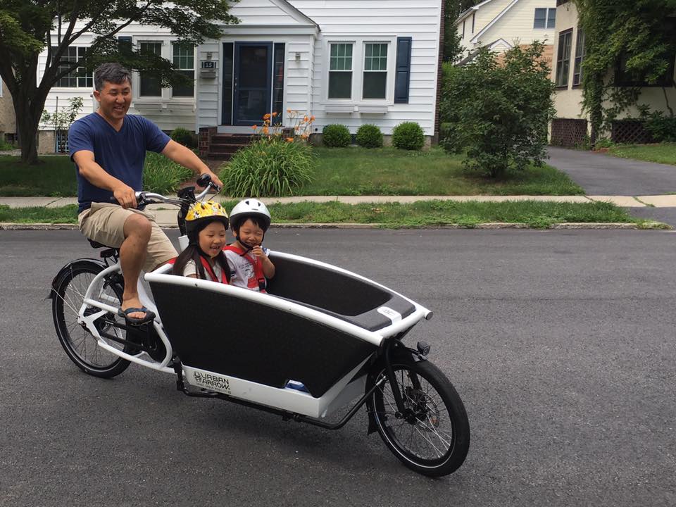 Person riding an ebike cargo bike with kids in it.
