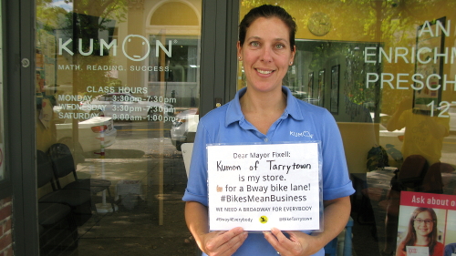 Merchant holding sign saying they want the bike lane on Broadway