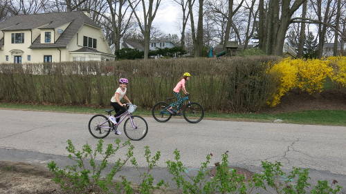 Photo of two kids cycling on a street.