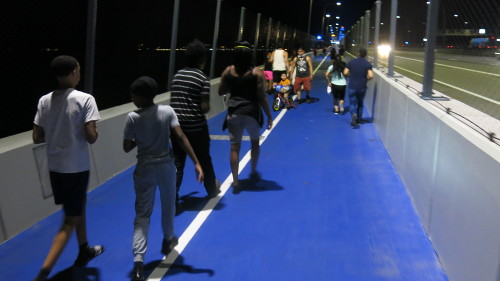 Loads of people walking on a bridge path.
