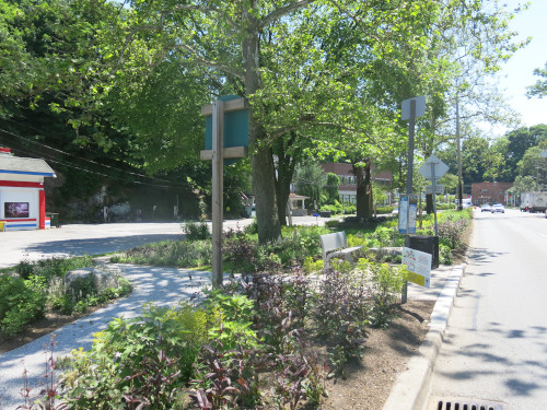 Photo of a newly landscaped large traffic island, with a bus stop bench and walkways to it.