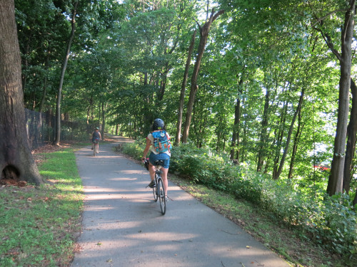 Two people riding on a shady trail.