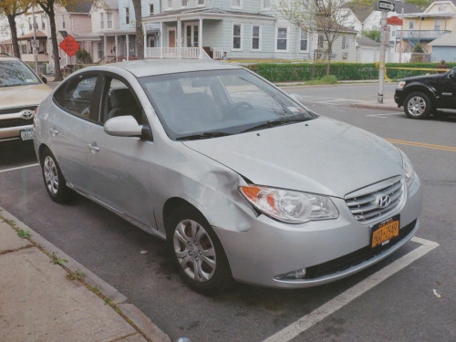 Photo of a silver car with a big dent on the front right panel between the wheel and headlight.
