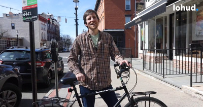 Man standing on a sidewalk holding a bike.