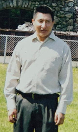 Photo of Luis Zhizhpon, standing in a park, wearing a white dress shirt and grey slacks.