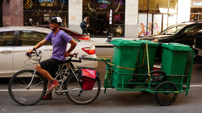 Bike trailer carrying 3 garbage cans