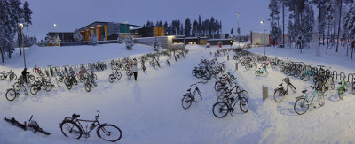 Photo of a snow covered school yard, with about a hundred bikes parked all around.