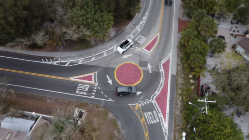 Aerial image of a three way intersection that has raised plastic roundabout in the middle and some raised plastic traffic islands.