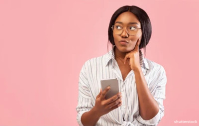 Photo of a woman thinking while holding a phone.